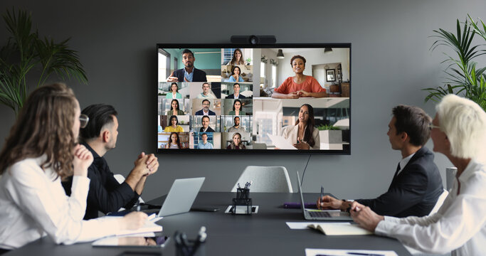 Group of multinational businesspeople, displayed on screen, engaged in videocall - Powered by Adobe