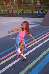 A stylish little preschool girl on a skateboard in a pose doing a trick.