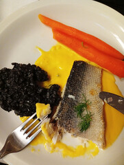 plate of grilled fish with vegetables and black rice