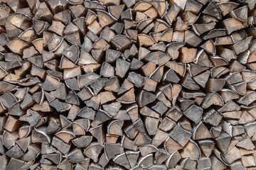 A pile of wood with many pieces of wood stacked on top of each other. The wood is brown and has a rough texture. Concept of rustic and natural beauty, as well as a feeling of warmth