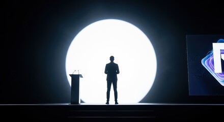 A lone figure stands on a brightly lit stage ready to present
