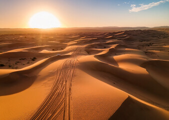 Deserto al tramonto con tracce di ruote