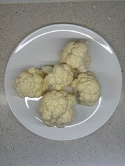 Cauliflower florets on a white plate. Natural organic vegetables, healthy eating, vegetarianism, and the production of vegetables.