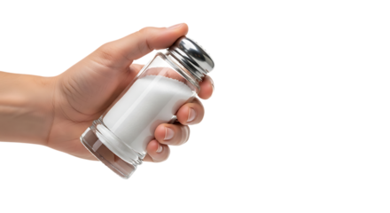 Close up of a human hand holding a glass salt shaker filled with white salt isolated on white background