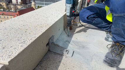A worker drills holes in concrete with a punch