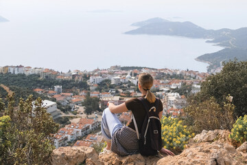 Young woman relaxing barefoot on rocky summit above coastal bays, embraces mindfulness and digital detox. Slow travel, wellness retreat energy—freedom, stillness and panoramic escape inspire balance.