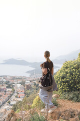 Young woman relaxing barefoot on rocky summit above coastal bays, embraces mindfulness and digital detox. Slow travel, wellness retreat energy—freedom, stillness and panoramic escape inspire balance.