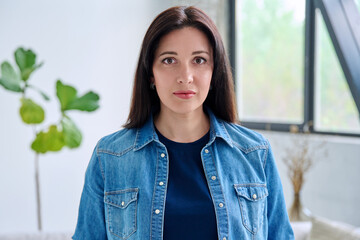 Headshot portrait of serious woman 30 years old inside room at home