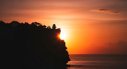 Silhouette of a temple on a cliff during a vibrant sunset over the ocean