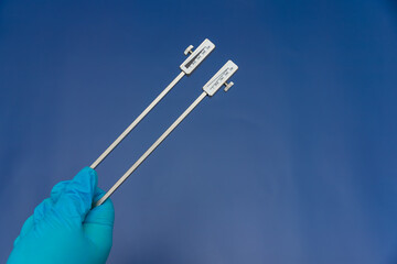 Blue Gloved Hands Holding tuning fork On blue Background, medical instruments in the hands of a...