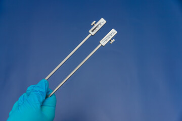 Blue Gloved Hands Holding tuning fork On blue Background, medical instruments in the hands of a...