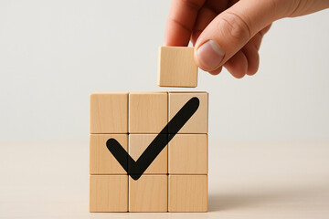 Professional photo of wooden blocks with bold black checkmark and hand placing final cube, symbolizing success, completion, reliability, achievement