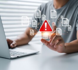 Person working on laptop with digital warning sign and document icons symbolizing data security breach