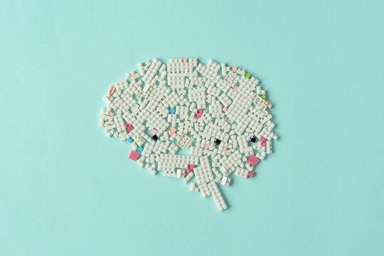 Creative brain shape made of white plastic blocks on pastel background symbolizing innovation, learning and modern technology.