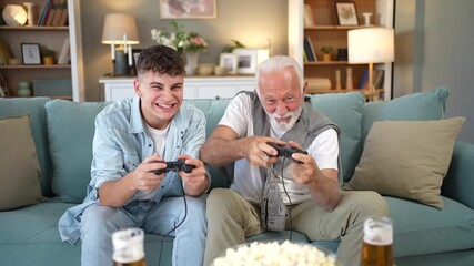 Grandfather and grandson playing video games together at home - Powered by Adobe