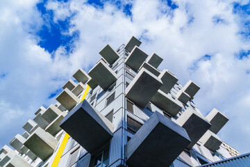 Contemporary residential building with projecting concrete balconies and yellow accent under bright...