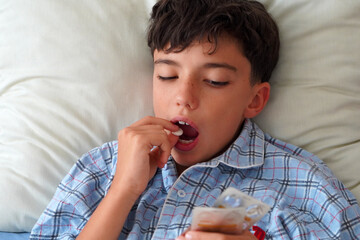child in pajamas sick in bed taking a cough pill