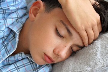 child health. Sick child in pajamas with a hand on his forehead. With a fever or headache.