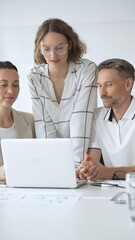 Obraz premium Professional team reviewing project data on laptop, working together in modern office environment, collaborating with focused corporate energy