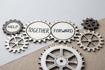 Gears demonstrating teamwork moving forward on a wooden surface
