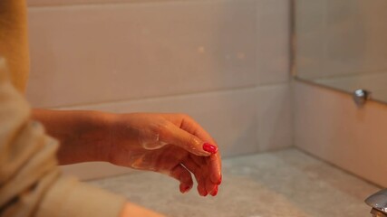 A woman washing  hands  under running water, demonstrating thorough hygiene practice against viruses and bacteria in a bathroom sink.