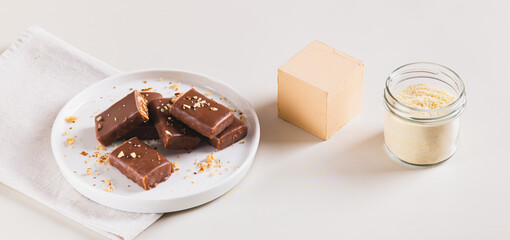 Protein bars with nuts on plate and protein powder in jar on table web banner