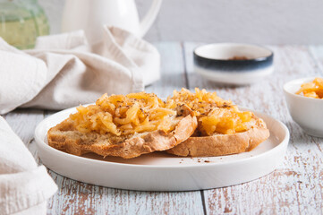 Appetizing croutons with stewed apple strips on a plate on the table