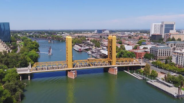 Aerial view of Sacramento, California, featuring the golden Tower Bridge, Sacramento River, downtown skyline, and boats along the riverbank.
