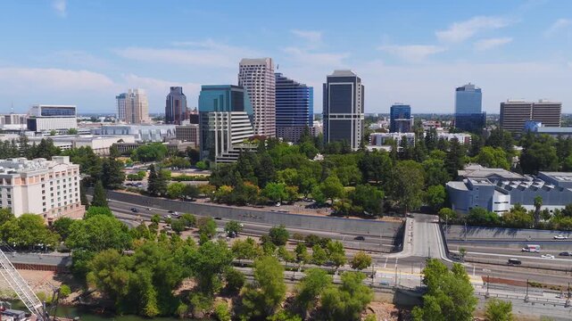 Aerial view of Sacramento, California, showing the Tower Bridge, State Capitol, skyline, Sacramento River, construction, and highway traffic on a sunny day.