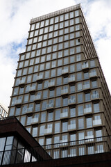 Obraz premium Modern, high rise building featuring sleek grid of windows, each with small balconies. Clean lines and geometric design reflect contemporary urban architecture, blending aesthetic appeal