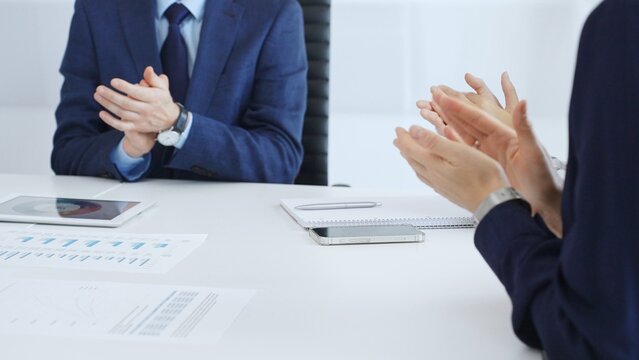 Professional business team clapping hands, celebrating successful presentation, showcasing collaborative spirit and corporate achievement in modern meeting space