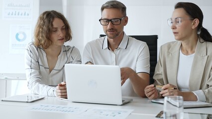 Professional team analyzing data on laptop, sharing insights during collaborative office meeting, highlighting workplace synergy and strategic planning. Business people concept