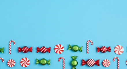 Festive holiday candy assortment featuring candy canes, striped sweets, and green foil-wrapped treats on a cheerful blue background