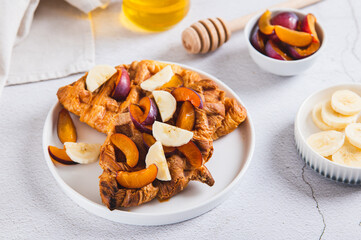 Croissant waffles with fruit and honey on a plate on a table