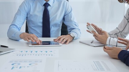 Business team working together, analyzing financial charts and data on digital tablet and smartphones, during a productive meeting in a modern office
