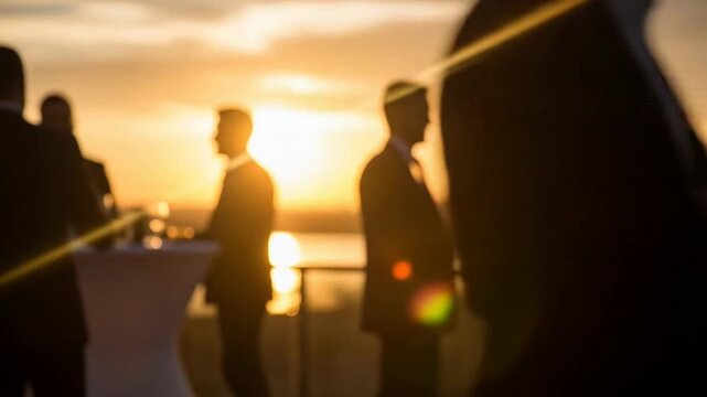 Silhouetted professionals networking during a vibrant sunset.