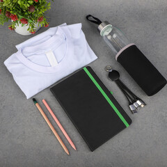 Minimal Office Desk Essentials With Notebook, Shirt, Water Bottle, Pencils, and Cables