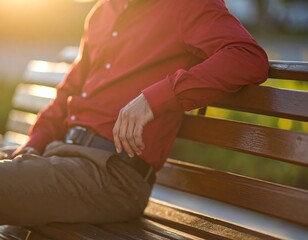 Obraz premium Man in red shirt sits on a park bench at sunset