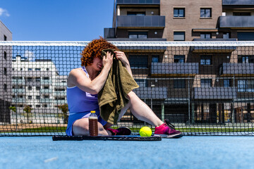 Female tennis player wiping sweat after training on a sunny day