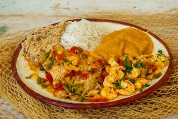 Brazilian moqueca capixaba is a typical dish from Espírito Santo, Brazil, with sea fish and shrimp, cooked in a clay pot and accompanied by white rice, pirão and farofa.