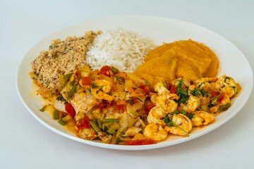 Brazilian moqueca capixaba is a typical dish from Espírito Santo, Brazil, with sea fish and shrimp, cooked in a clay pot and accompanied by white rice, pirão and farofa.
