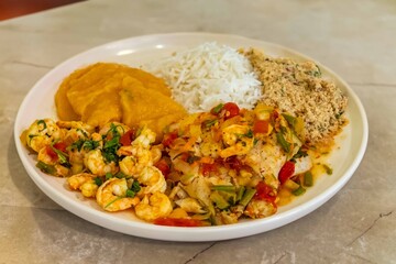 Brazilian moqueca capixaba is a typical dish from Espírito Santo, Brazil, with sea fish and shrimp, cooked in a clay pot and accompanied by white rice, pirão and farofa.