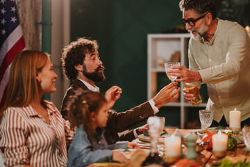 Family celebrating thanksgiving toasting with wine in front of usa flag