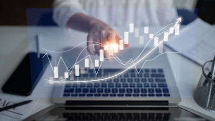 A businessperson examines financial data on a laptop screen, highlighting graph trends and digital...