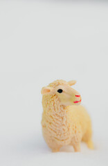 One toy yellow sheep on a snowy background.