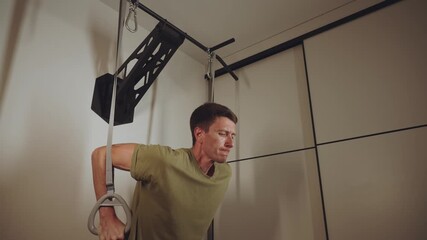 A man pushes during a physical exercise, push-ups on rings - Powered by Adobe