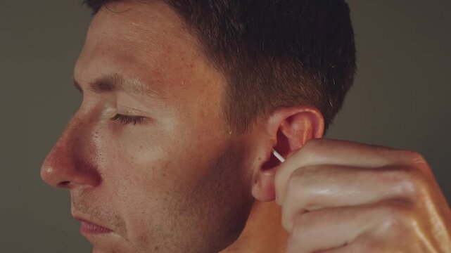 A man cleans his ears, clean his ears with a cotton swab