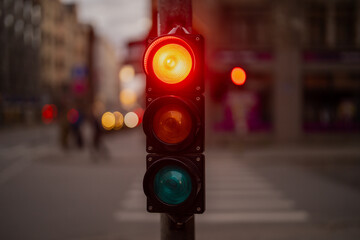 Detailed view of red urban traffic light with signal lamp and crosswalk in background, illustrating...