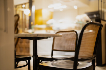 Inviting cafe scene with soft blurred background, warm yellow tones and empty chairs around marble table, peaceful moment capturing charm of modern dining and relaxed social environment