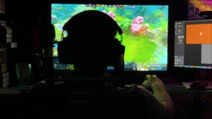 Man playing video game at computer in the dark gaming night. Gamer streaming online video e-sport, entertainment, and digital technology. Pc monitor. Focused fun guy play. Tech leisure, hobby. - Powered by Adobe